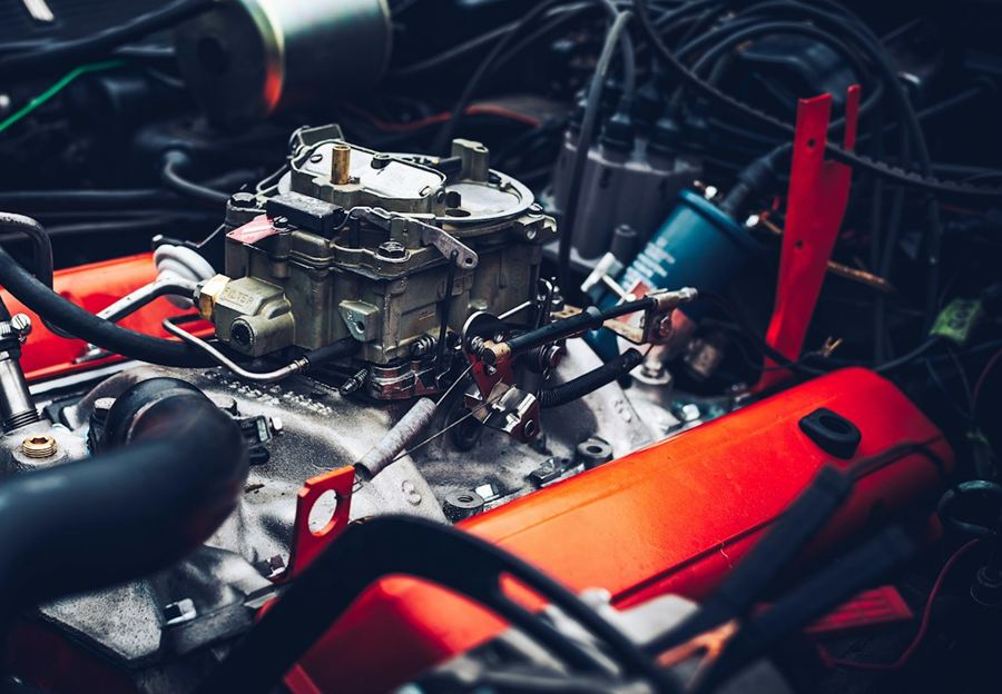 Engine bay with a carburetor and red valve covers